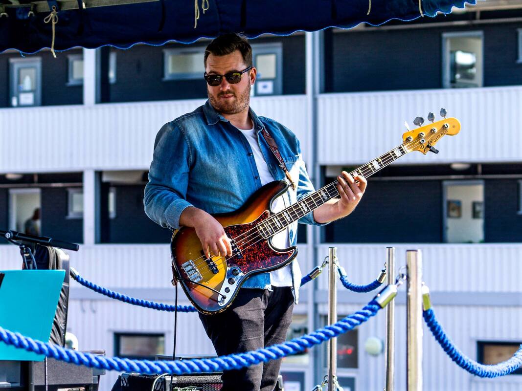 Jack Collier playing his sunburst bass guitar in the sun