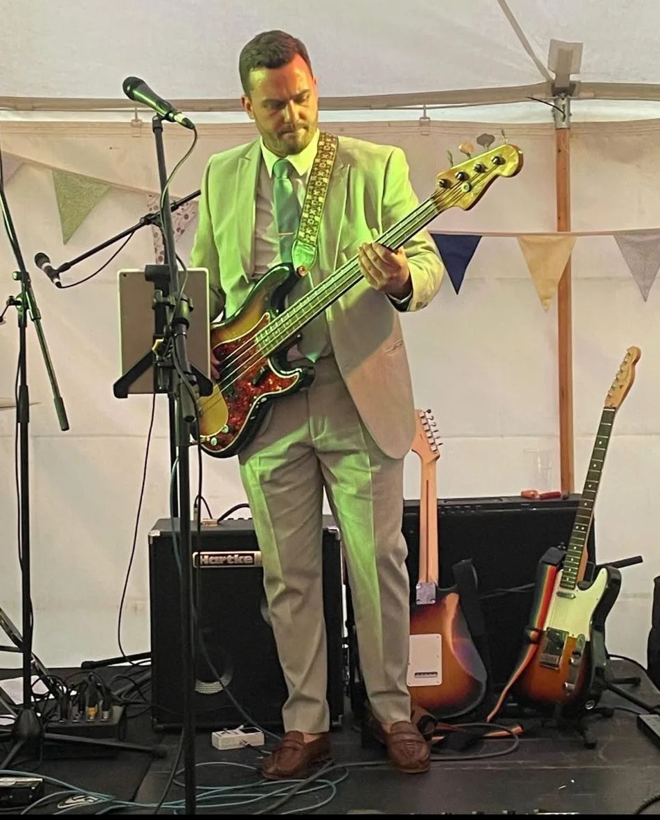 Jack Collier in a suit performing on bass at a marquee event