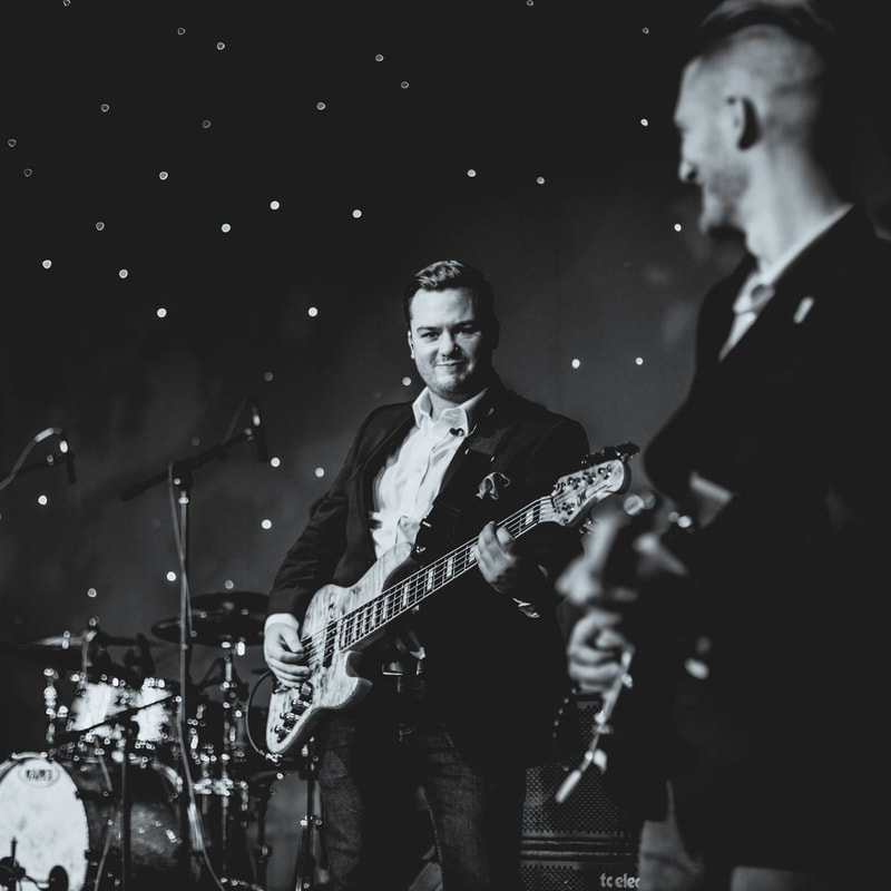 Jack in a blazer performing bass at a formal event